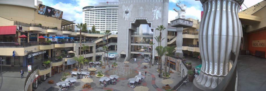 Aerial view of Hollywood and Highland Center showing Egyptian-style architecture with elephant statue, multiple shopping levels, palm trees, and outdoor plaza in Los Angeles