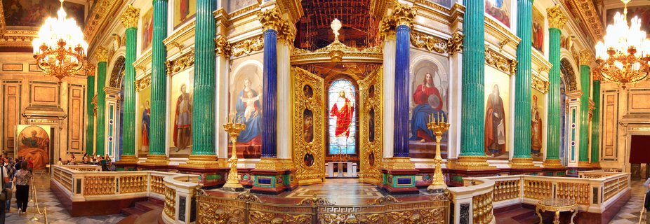 Interior view of Saint Isaac's Cathedral showing green malachite columns, blue lapis lazuli columns, golden iconostasis with religious paintings, ornate chandeliers, and visitors on marble floors