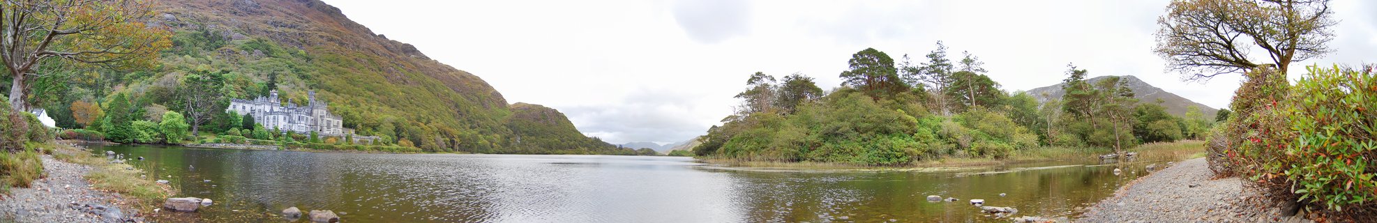 Kylemore Abbey castle building on lakeshore with mountains and trees in Connemara Ireland