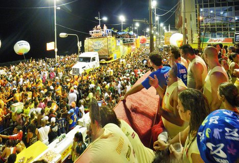 Large crowd of people at night following a decorated sound truck with performers during Carnival in Salvador Brazil