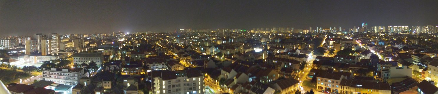 Night aerial view of Singapore showing illuminated residential buildings, apartment blocks, and street lights across an urban neighborhood