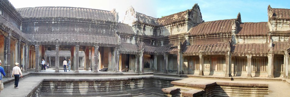 Stone columns and corridors inside Angkor Wat temple with visitors walking through ancient Khmer architecture under clear sky