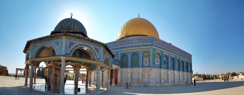 Panoramic view of the golden Dome of the Rock Islamic shrine with blue tiled walls next to the ornate Dome of Chain fountain with marble columns on Temple Mount plaza in Jerusalem under clear blue sky