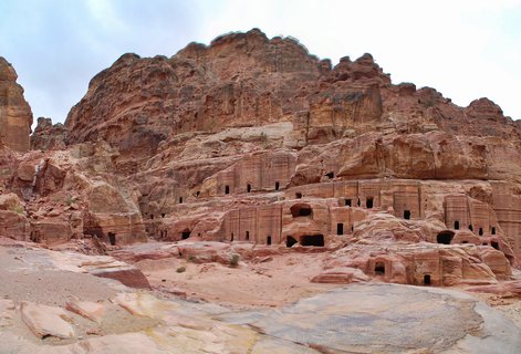 Multiple ancient tomb facades carved into rose-red sandstone cliffs at Petra's Street of Facades archaeological site in Jordan