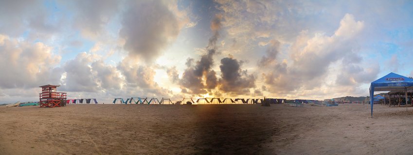 Sunset over Canoa Beach with lifeguard tower and vendor tents, Ecuador