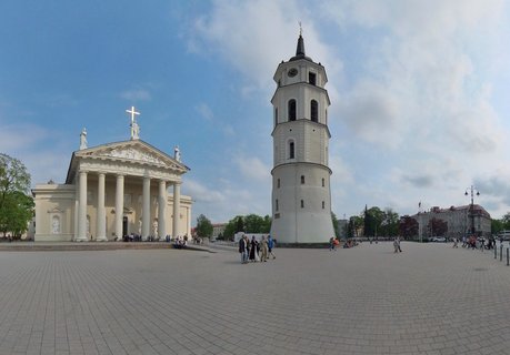 Vilnius Cathedral with white columns and Bell Tower on Cathedral Square in Lithuania with people walking on paved plaza