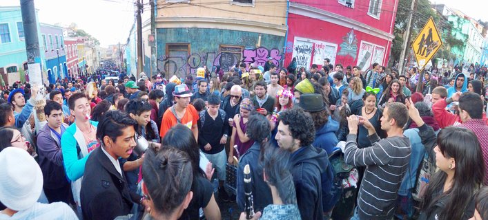Large crowd of people at street festival surrounded by colorful buildings covered in graffiti and street art in Santiago, Chile