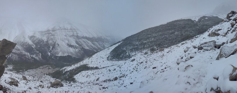 Snow-covered mountain peaks and rocky slopes in Torres del Paine National Park, Chile, with foggy overcast sky