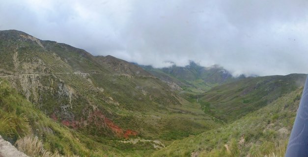 Mountain valley in Argentina with a winding road on green hillsides under cloudy sky