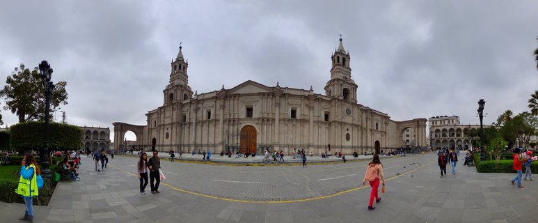 Large white stone cathedral with two bell towers in a paved plaza with people walking, Arequipa Peru