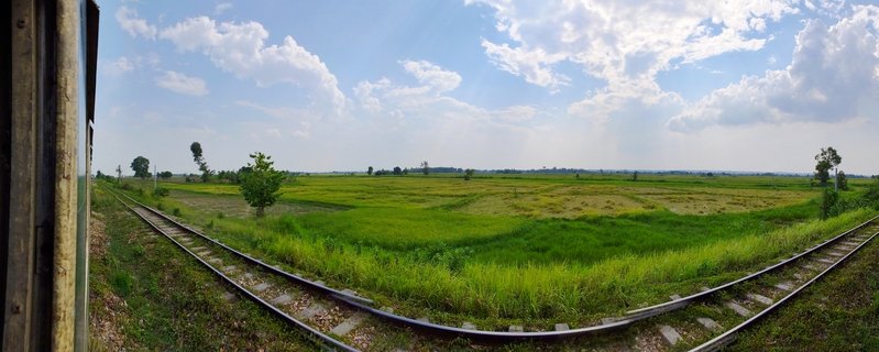 Railway tracks curve through rice paddies in rural Myanmar countryside