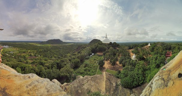 Panoramic landscape showing white Buddhist stupas on rocky hills surrounded by green tropical forest in Polonnaruwa, Sri Lanka