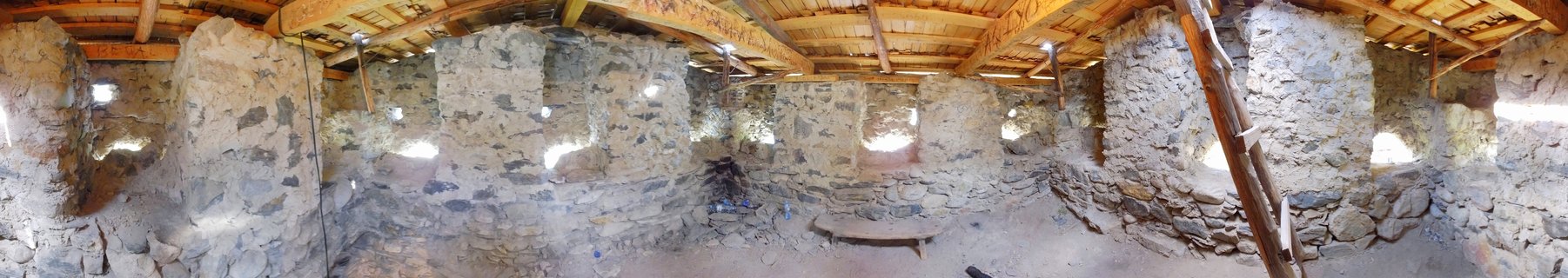 Panoramic interior of medieval stone tower house with rough stone walls, small windows, and wooden beam ceiling in Mestia, Georgia