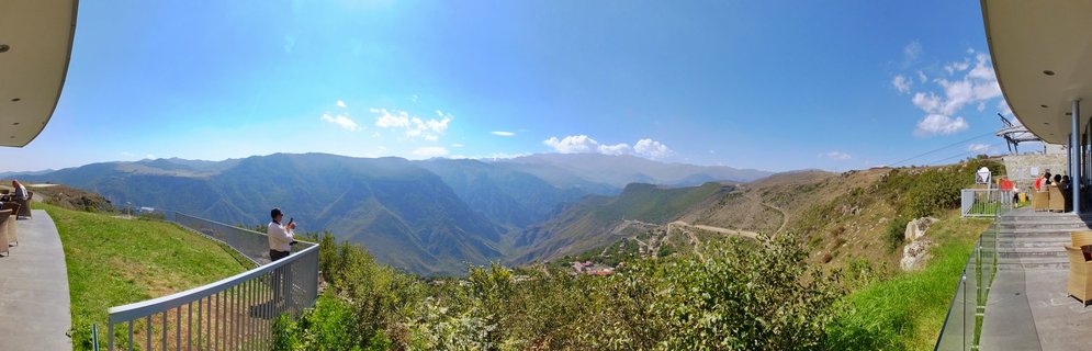 Panoramic mountain landscape view from a cableway station terrace showing green valleys, layered mountain ranges, and clear blue sky in Tatev, Armenia