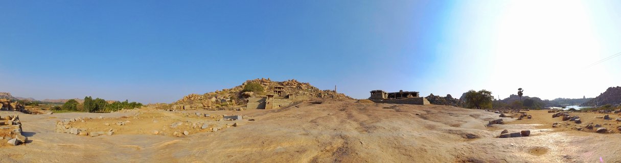 Ancient stone temple ruins on rocky terrain with scattered boulders, clear blue sky, Hampi heritage site India