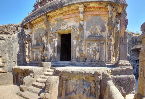Ancient Hindu rock-cut temple with carved stone pillars, sculpted figures, and ornate friezes at Ellora Caves in Aurangabad, India