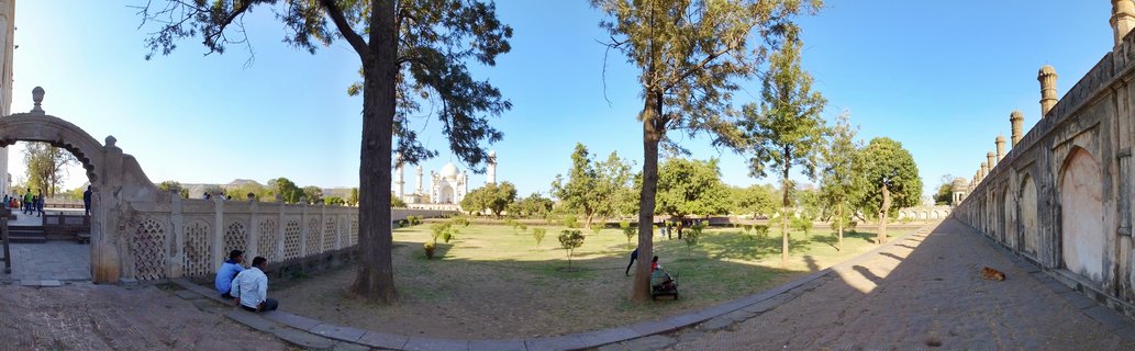 Wide view of Bibi Ka Maqbara mausoleum with gardens, stone walls with arches, trees, and visitors in Aurangabad, India