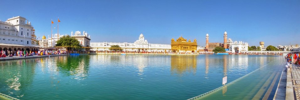 Golden Temple in Amritsar, India—a gold-plated Sikh gurdwara surrounded by turquoise sacred pool with white marble buildings and pilgrims under blue sky