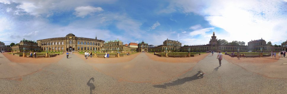 Panoramic view of the Zwinger Palace courtyard in Dresden showing Baroque buildings with domes, statues, fountains, and visitors walking on gravel paths under blue sky