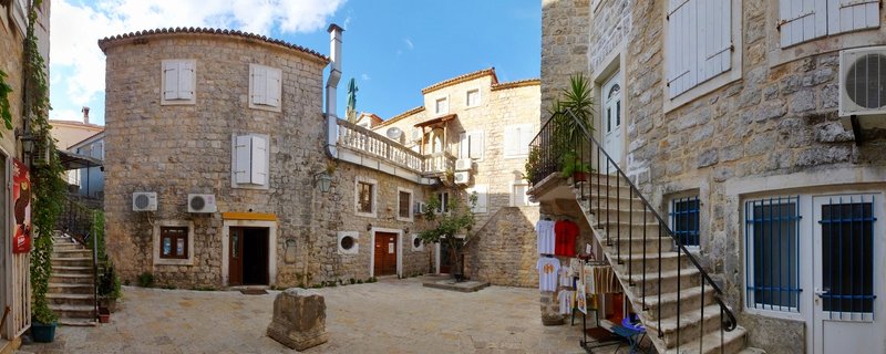 Stone courtyard with central palm tree surrounded by historic Mediterranean buildings in Budva Old Town, Montenegro