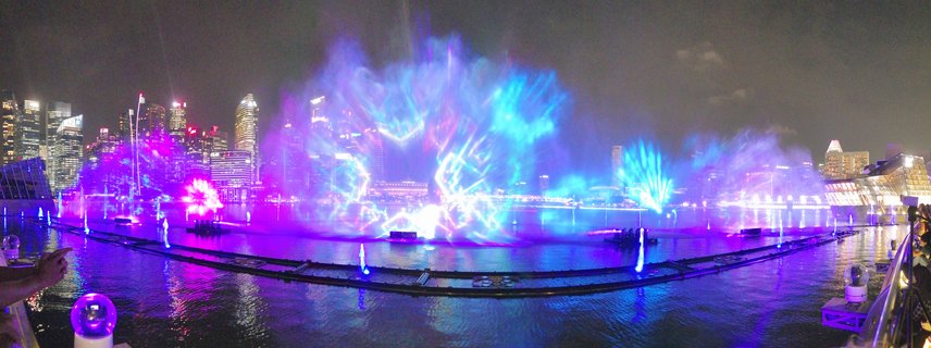 Night view of the Spectra light and water show at Marina Bay Singapore with colorful purple and blue fountain projections and illuminated city skyline in the background