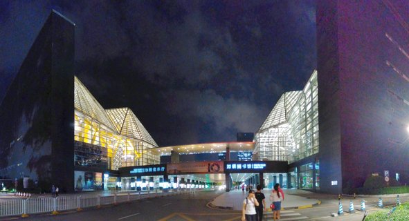 Night photograph of Shenzhen Concert Hall and Library with two illuminated glass pyramid structures connected by a central building, people walking in foreground