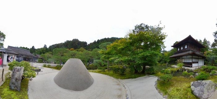 Traditional Japanese temple pavilion beside a cone-shaped sand mound in a raked gravel Zen garden with moss, trees, and visitors at Ginkaku-ji Kyoto