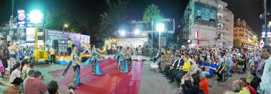 Four Thai traditional dancers in blue and gold costumes perform on a red stage at night while a large audience watches on Khao San Road in Bangkok