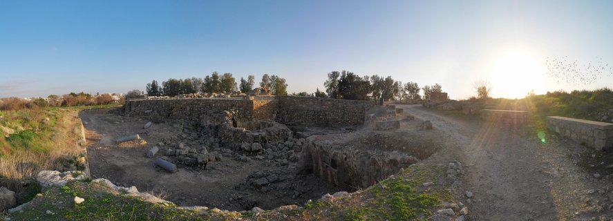 Archaeological ruins with ancient stone walls and scattered columns at sunset in Paphos, Cyprus