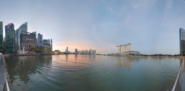 Panoramic cityscape of Singapore Marina Bay at sunset showing Marina Bay Sands hotel, skyscrapers, and water reflections