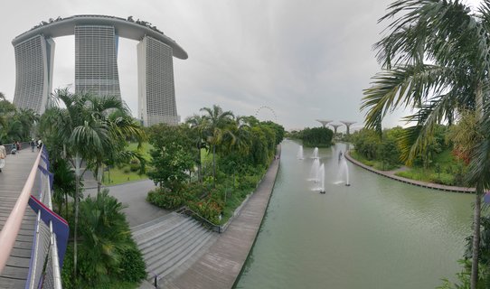 Marina Bay Sands hotel with three towers and sky bridge overlooking a waterway with fountains, surrounded by palm trees and tropical gardens in Singapore
