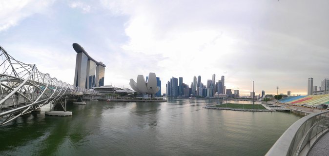 Panoramic view of Singapore's Marina Bay showing Marina Bay Sands hotel, ArtScience Museum, Helix Bridge, and CBD skyscrapers across the waterfront